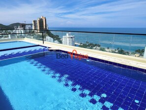 A rooftop swimming pool with clear blue water, surrounded by a glass barrier. - Apartasuites Vita 945 - By Bedviajes (Santa Marta)
