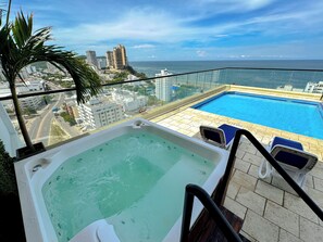 Una piscina en la azotea con vistas al océano y al paisaje urbano.