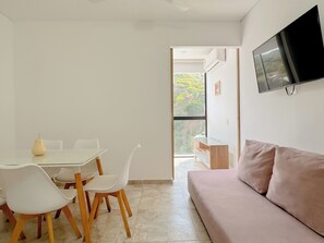 A modern living room with a sofa, a TV mounted on the wall, and a dining area with chairs and a table. - Apartasuites Vita 945 - By Bedviajes (Santa Marta)