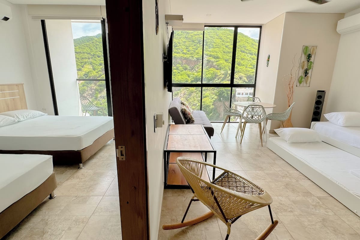 Une chambre moderne avec deux lits, une table à manger et une vue sur une végétation luxuriante.