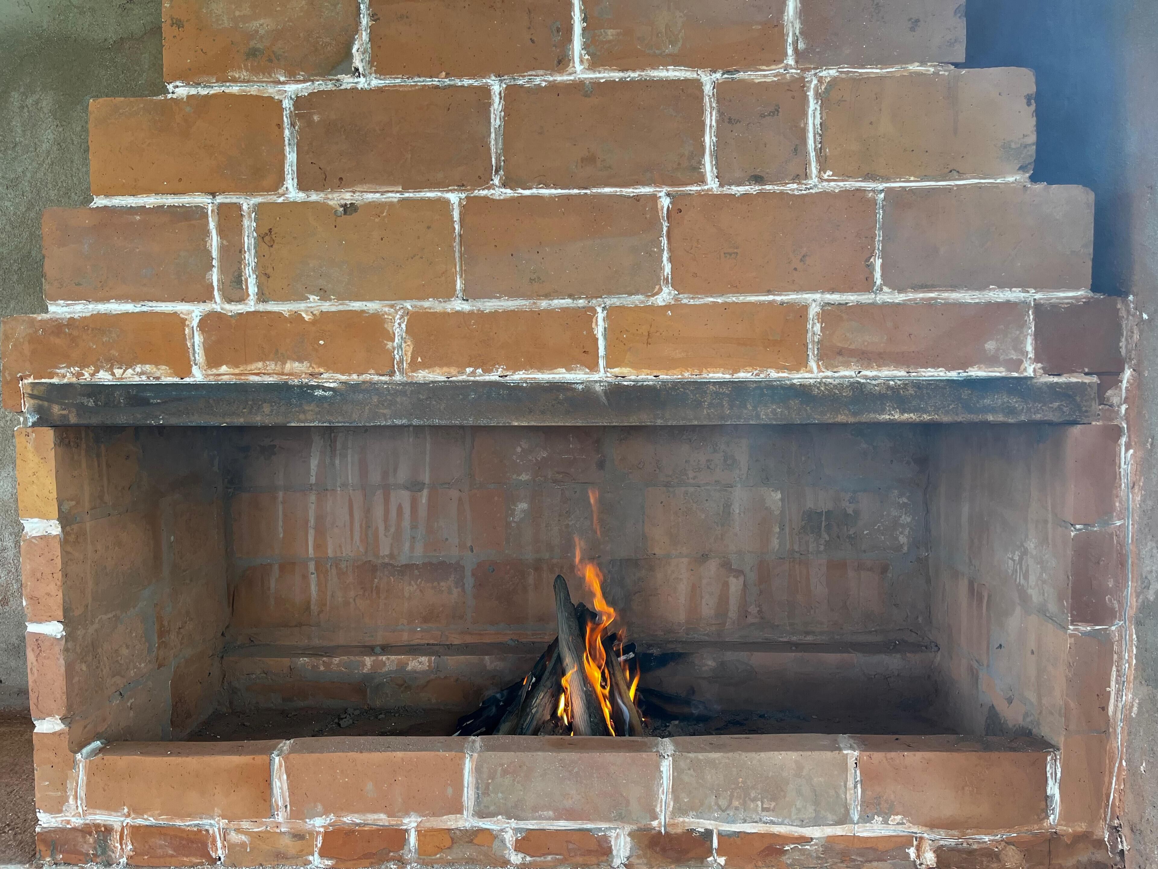 A brick fireplace with a fire burning inside.