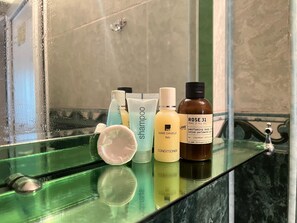 A bathroom shelf with various toiletries including a shampoo bottle, conditioner, and a perfume bottle. - La Casa de Habel (Quba)