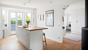 A modern kitchen with a central island, white cabinetry, and a view to the outdoors. - Ref. 673271 (Täby)
