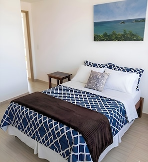 Un letto con una coperta a motivi geometrici, una coperta in stile patchwork marrone e due cuscini decorati con un disegno geometrico.