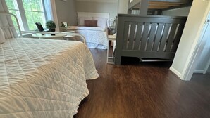 A bedroom with a large bed, a desk, and a chair. There is a window with curtains and a view of greenery outside. - Lazy Days on Neely Henry with kayaks and floating mat! (Ashville)