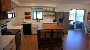 Una cocina moderna con una isla central, electrodomésticos integrados y vistas a un balcón.
