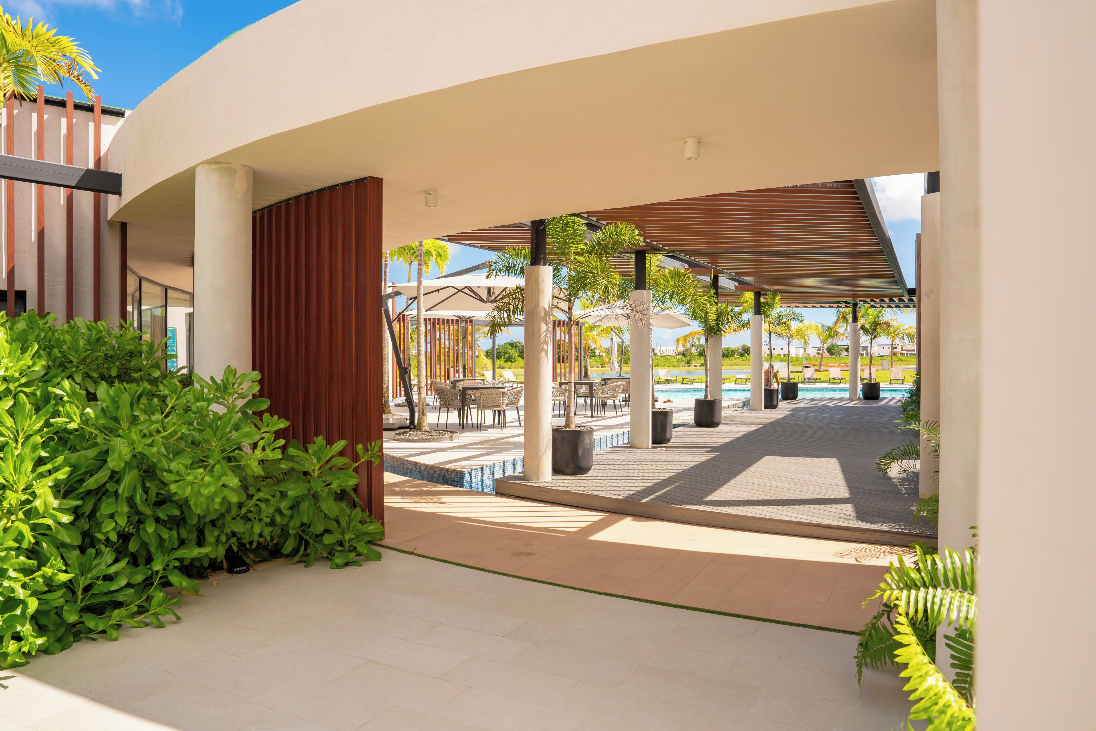 Un espacio exterior moderno con piscina, mobiliario y palmeras.