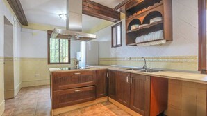 A kitchen with wooden cabinets, a stainless steel range hood, and a window providing natural light. - Casa Rural El Pantano Peñarroya-Pueblonuevo by Ruralidays (Córdoba)
