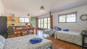 A room with two beds, a dining area, and a kitchenette. - Casa Rural El Pantano Peñarroya-Pueblonuevo by Ruralidays (Córdoba)