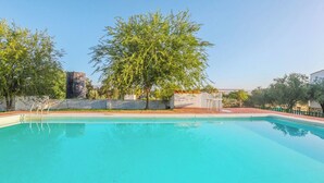 A swimming pool with clear blue water, surrounded by a low brick wall and trees. - Casa Rural El Pantano Peñarroya-Pueblonuevo by Ruralidays (Córdoba)