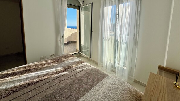 A bedroom with a bed, a sliding glass door leading to a balcony, and sheer curtains. - Beautiful triplex with sea views in Mijas Costa Calalucia! (Mijas-Costa)