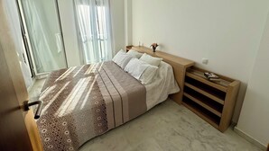 A bedroom with a bed, a nightstand, a wooden bench, and a sliding glass door leading to a balcony. - Beautiful triplex with sea views in Mijas Costa Calalucia! (Mijas-Costa)