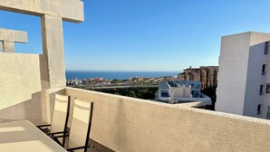 A balcony with a table and chairs, overlooking a coastal town and the sea. - Beautiful triplex with sea views in Mijas Costa Calalucia! (Mijas-Costa)