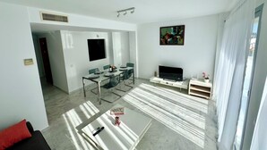 A modern living room with a dining area, a flat-screen TV, and a painting on the wall. - Beautiful triplex with sea views in Mijas Costa Calalucia! (Mijas-Costa)