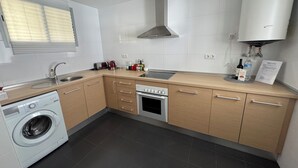 A modern kitchen with a built-in washing machine, a stove, and a sink. - Beautiful triplex with sea views in Mijas Costa Calalucia! (Mijas-Costa)