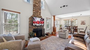A spacious living room with a stone fireplace, comfortable seating, and a dining area.
