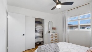 A bedroom with a bed, a wardrobe, a mirror, and a window.