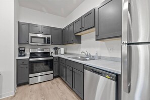 A modern kitchen with stainless steel appliances, grey cabinetry, and a dishwasher.