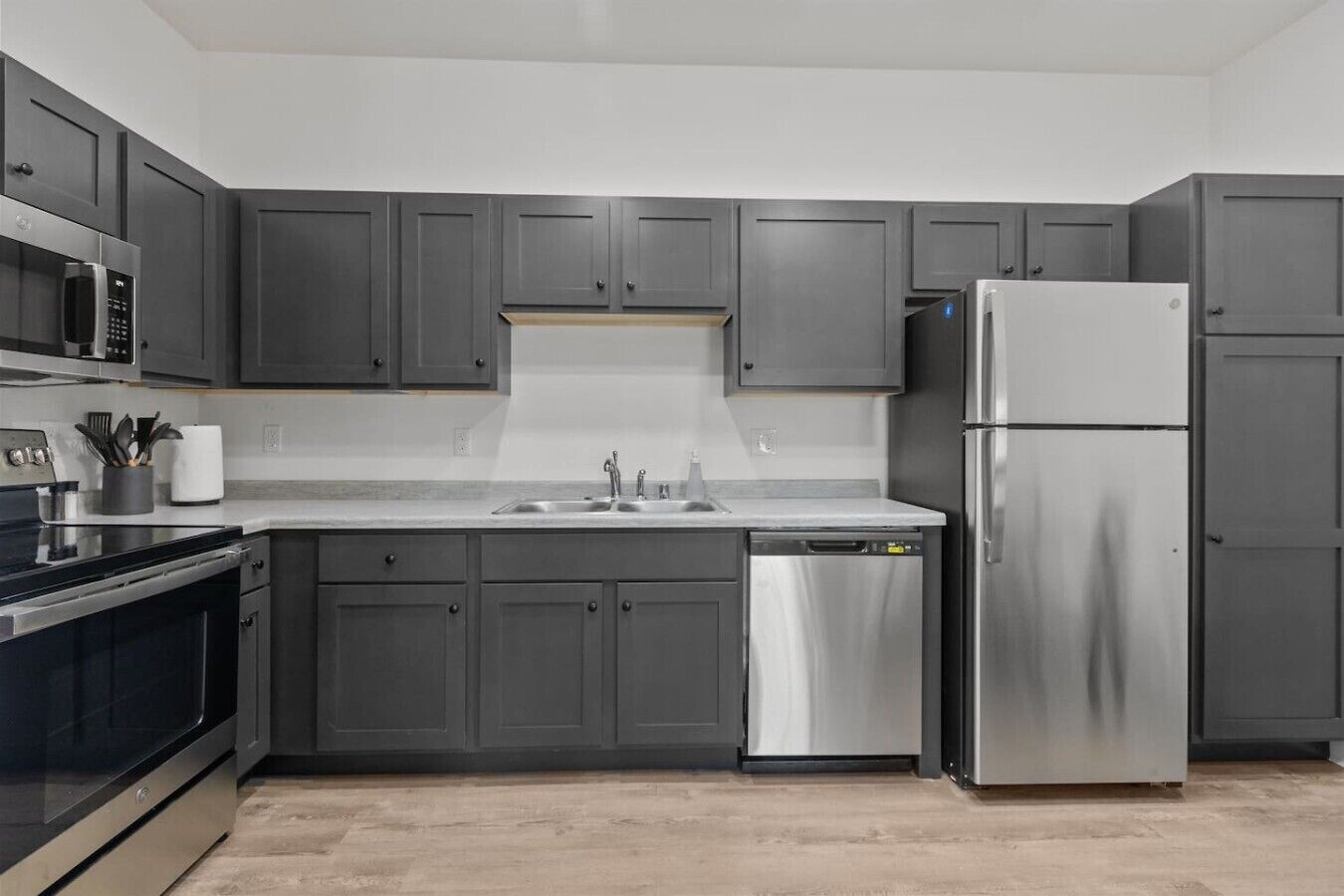 A modern kitchen with grey cabinetry, stainless steel appliances, and a dishwasher.