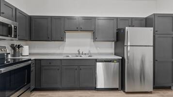 A modern kitchen with grey cabinetry, stainless steel appliances, and a dishwasher.