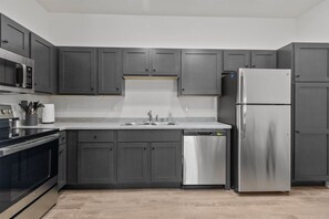 Una cocina moderna con armarios grises, electrodomésticos de acero inoxidable y lavavajillas.