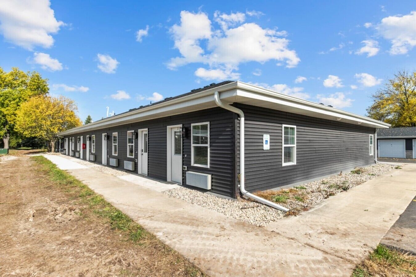 A row of single-story mobile homes with a concrete pathway in front.