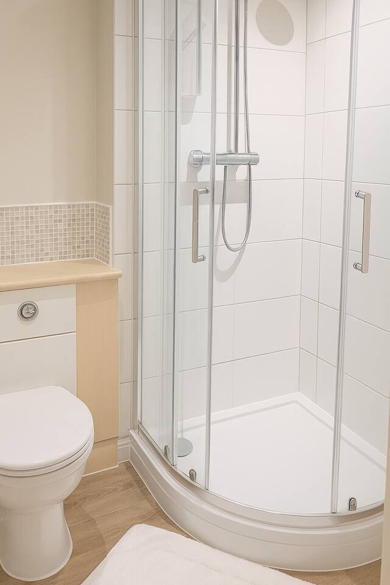 A modern bathroom with a glass-enclosed shower, a toilet, and a vanity with a tiled backsplash.