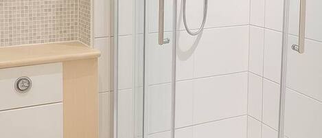 A modern bathroom with a glass-enclosed shower, a toilet, and a vanity with a tiled backsplash.