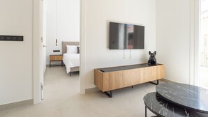 A modern hotel room with a wooden console table, a black marble table, a flat-screen TV mounted on the wall, and a bed with a white headboard. - 2-bedroom apartment in fantastic Malaga (Málaga)