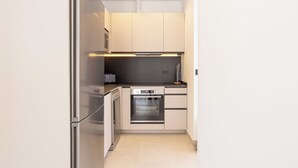 A modern kitchen with stainless steel appliances, white cabinetry, and a black countertop. - 2-bedroom apartment in fantastic Malaga (Málaga)