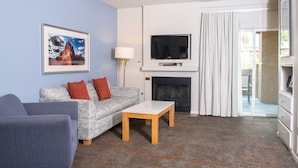 Una sala de estar con un sofá, una mesa de centro, un televisor de pantalla plana, una chimenea y un cuadro en la pared.