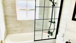 Un baño con bañera, cabina de ducha, ventana y suelo de mármol.