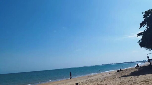 Una playa con cielos despejados y aguas tranquilas.
