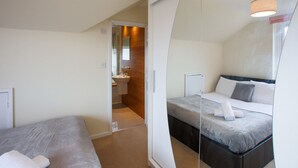 A modern bedroom with a bed, a bedside table, and a mirror. - Grand 5BR Home in Market Harborough with Free Parking (Dingley)