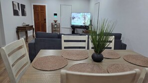 A dining area with a wooden table, woven placemats, and a vase of green plants. - Historic, Modern & Cozy 3-Bedroom Home Near Downtown Tulsa & Greenwood District (Tulsa)