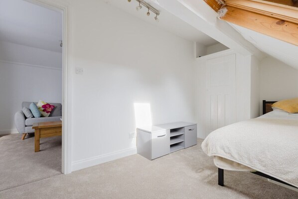 A bedroom with a bed, a desk, a chair, and a wardrobe.