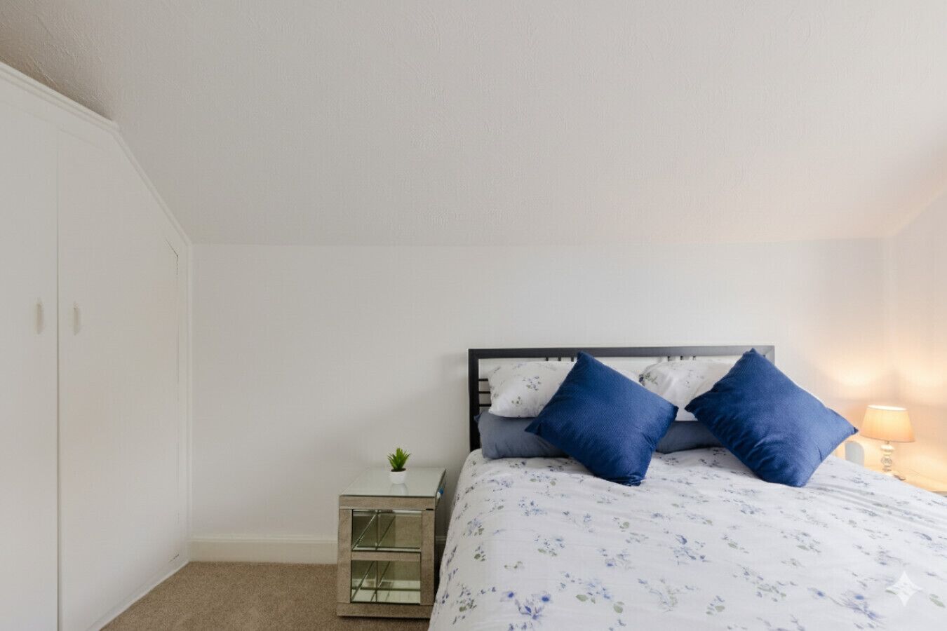 Une chambre à coucher avec un lit, une table de chevet et une lampe.
