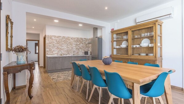 Une cuisine moderne avec un pare-feu en pierre, un coin repas avec une table en bois et des chaises bleues, et un meuble en bois contenant de la vaisselle.
