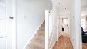 A staircase leading to a kitchen with white walls and wooden flooring.
