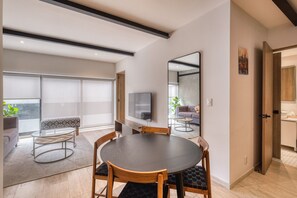 A modern living room with a dining table, sofa, and TV.
