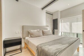 Ein modernes Schlafzimmer mit Bett, Nachttisch und Blick ins Freie.