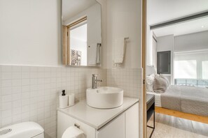 Ein modernes Badezimmer mit einem weißen Waschbecken, einer Toilette und einem Spiegel.