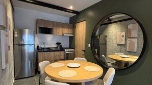 A modern kitchen with a round dining table, chairs, and a built-in oven. - Casa Corona - 1BR in Roma Norte - HighF (Mexico City)