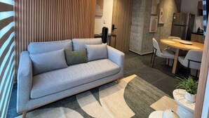 A modern living room with a sofa, a dining area with a table and chairs, and a kitchen area with appliances. - Casa Corona - 1BR in Roma Norte - HighF (Mexico City)