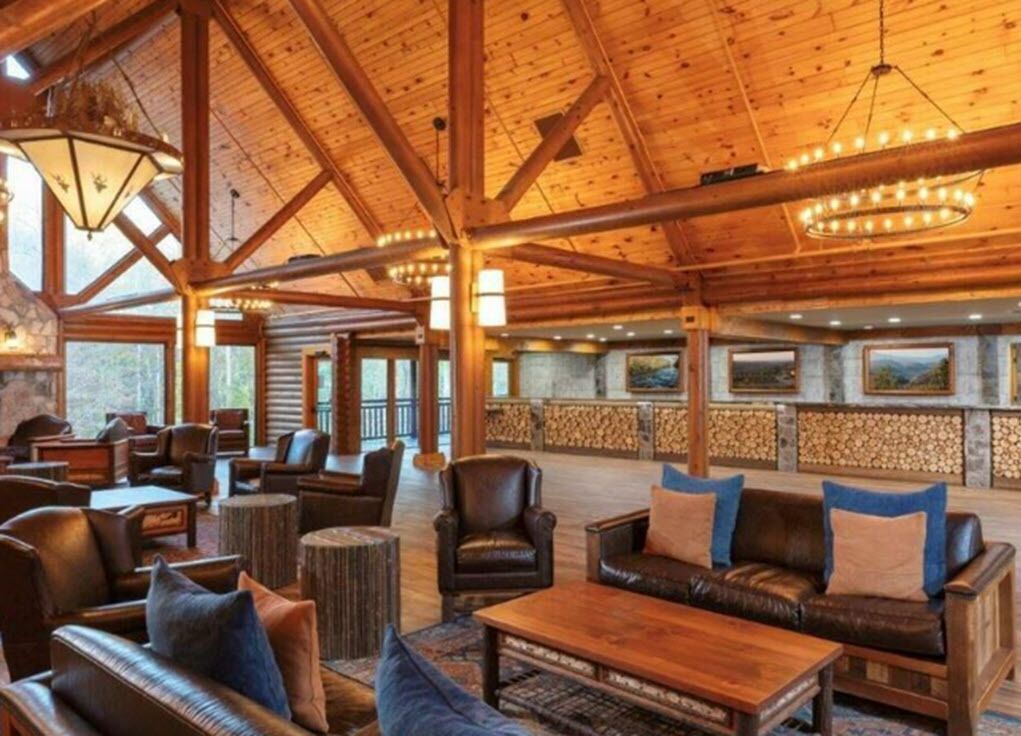 A spacious lobby with wooden beams, leather sofas, and a stone fireplace.