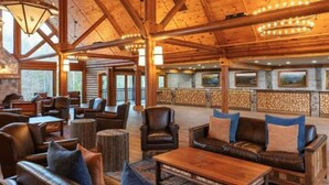 Eine geräumige Lobby mit Holzbalken, Ledersofas und einem Kamin aus Stein.