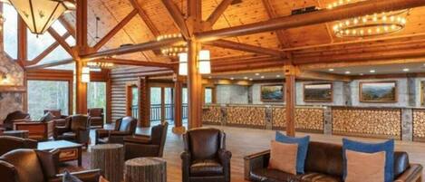 A spacious lobby with wooden beams, leather sofas, and a stone fireplace.