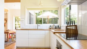 Una cucina moderna con mobili bianchi, un piano di lavoro in legno e un'ampia finestra con un ombrello.