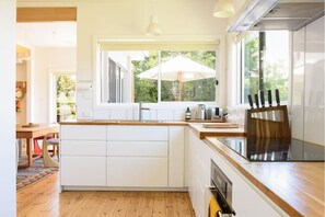 Een moderne keuken met witte kastjes, een houten aanrecht en een groot raam met een parasol.
