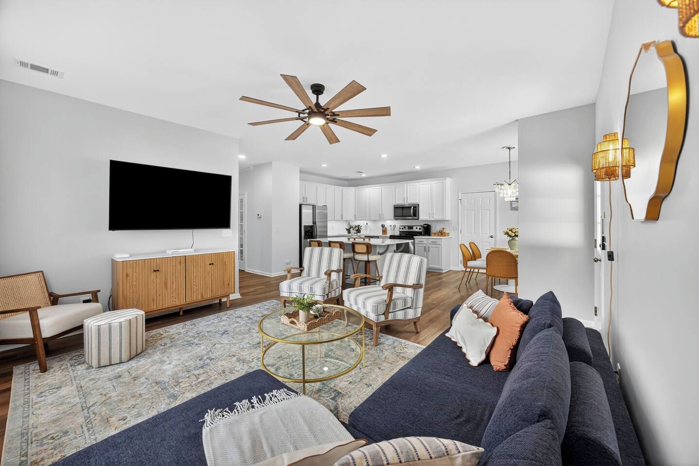 A modern living room with a sofa, armchairs, a coffee table, and a TV.